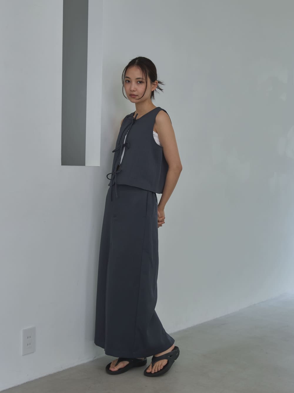 グレー系のベスト、ホワイト系のキャミソール、グレー系のスカートを着用したレディースの夏コーディネートの2枚目の写真