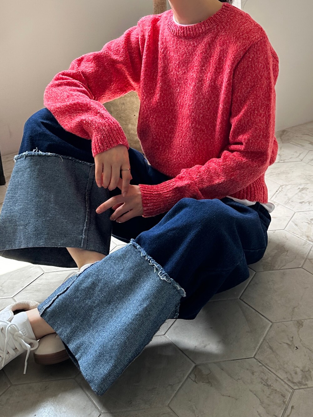 レッド系のニット/セーター、ブルー系のデニムパンツを着用したレディースの秋コーディネートの4枚目の写真