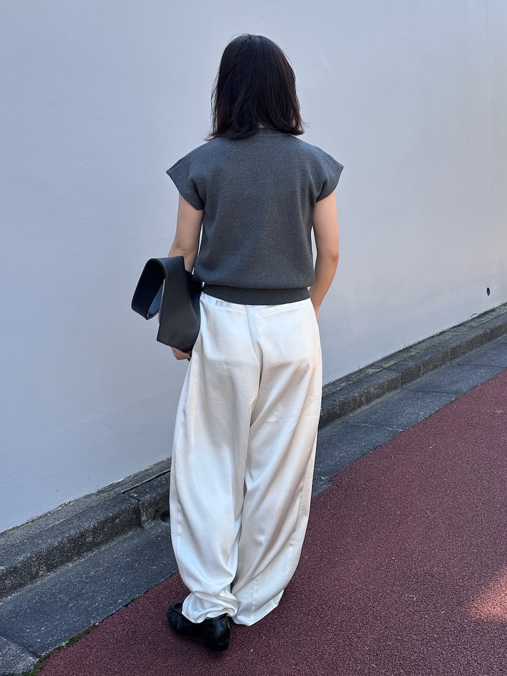 グレー系のニット/セーター、ブラック系のショルダーバッグ、ホワイト系のその他パンツを着用したレディースの春コーディネートの3枚目の写真