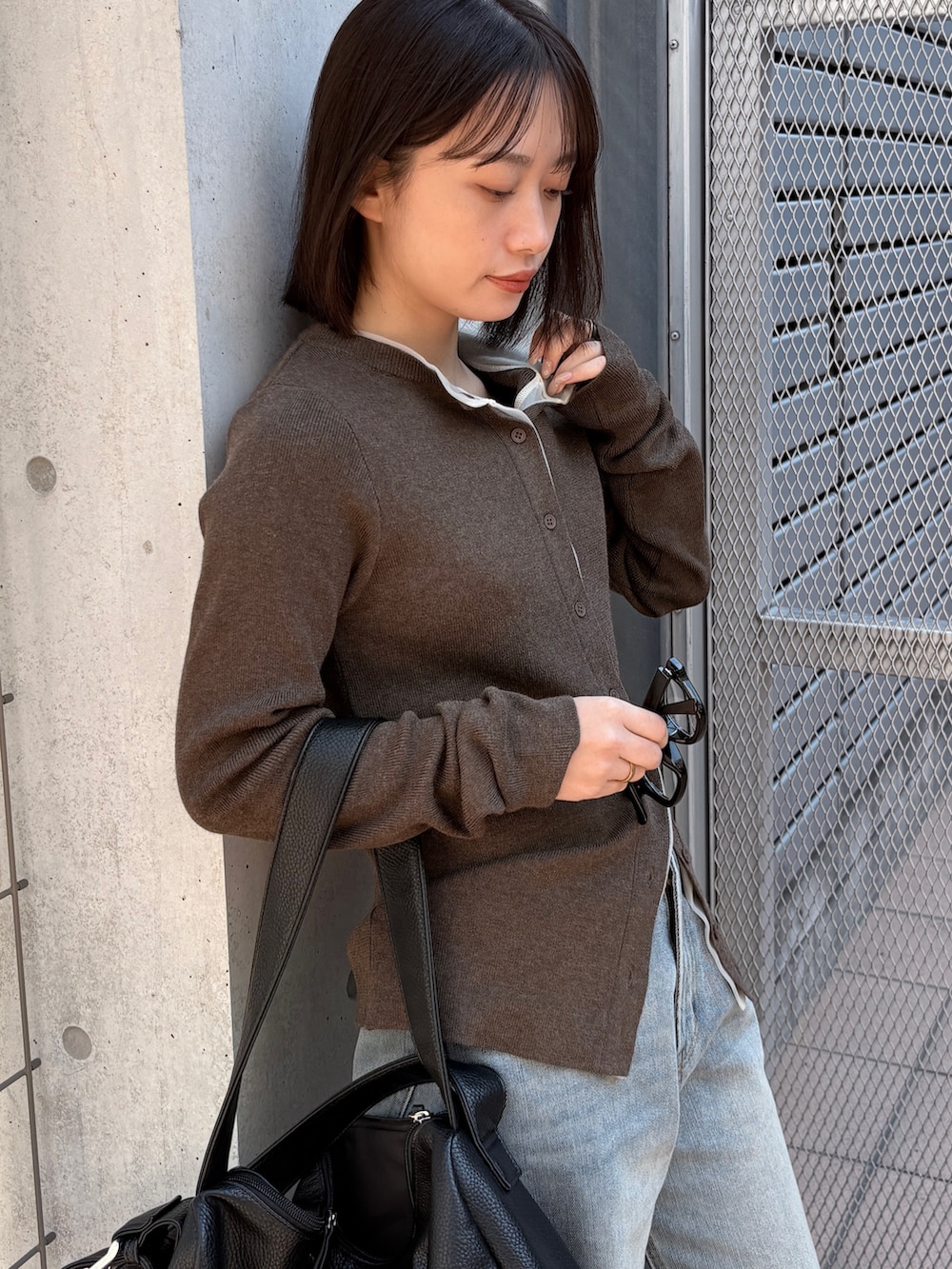 ブラウン系のカーディガン/ボレロ、ブルー系のデニムパンツ、ブラック系のショルダーバッグを着用したレディースの春コーディネートの3枚目の写真