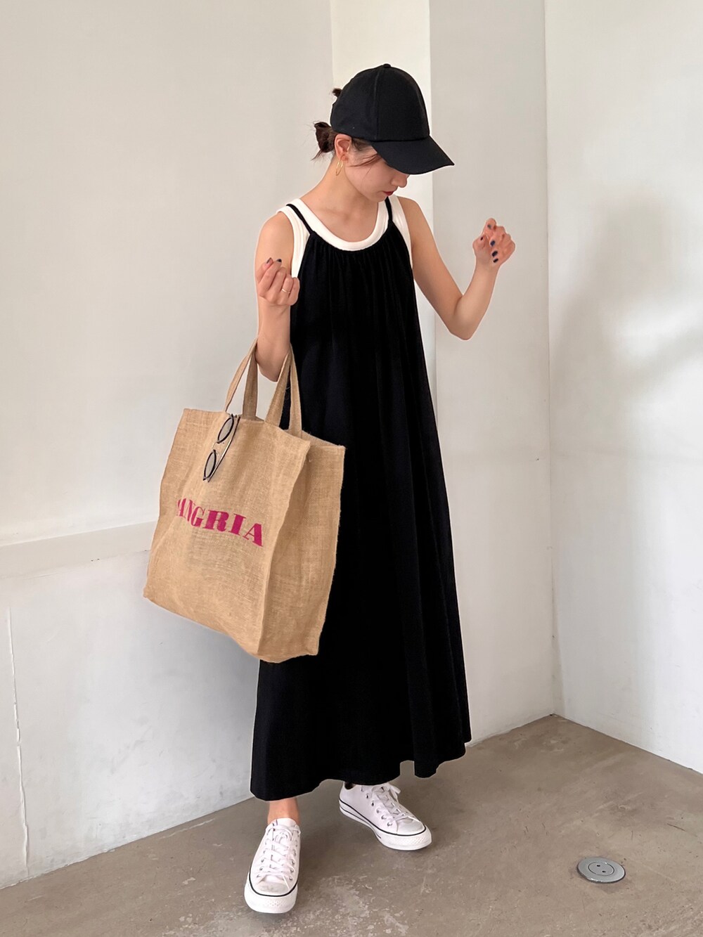 パープル系のトートバッグ、ホワイト系のスニーカー、ブラック系のワンピースを着用したレディースの夏コーディネートの2枚目の写真