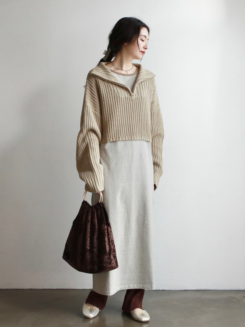 ベージュ系のワンピース、ブラウン系のハンドバッグ、ゴールド系のバレエシューズを着用したレディースの冬コーディネートの3枚目の写真