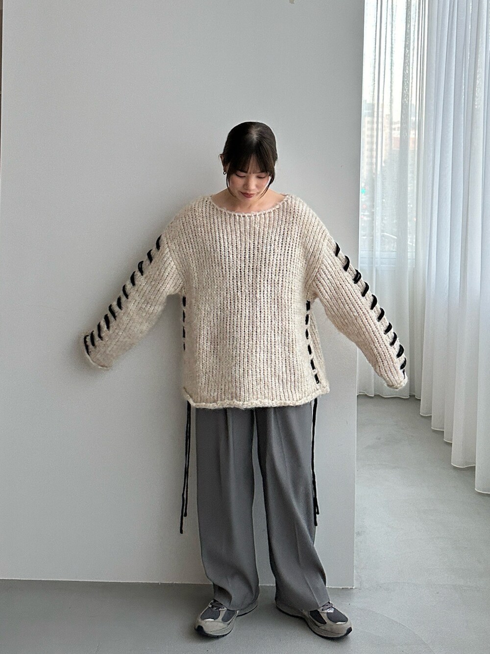 ホワイト系のニット/セーター、ブラック系のスラックスを着用したレディースの秋コーディネートの3枚目の写真