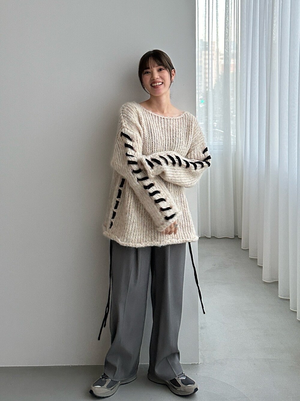 ホワイト系のニット/セーター、ブラック系のスラックスを着用したレディースの秋コーディネートの2枚目の写真