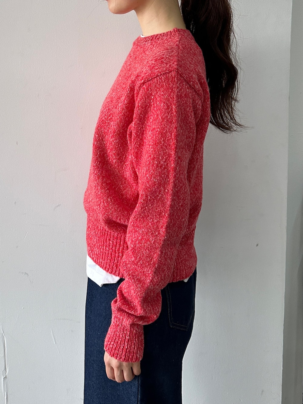 レッド系のニット/セーター、ブルー系のデニムパンツを着用したレディースの秋コーディネートの3枚目の写真