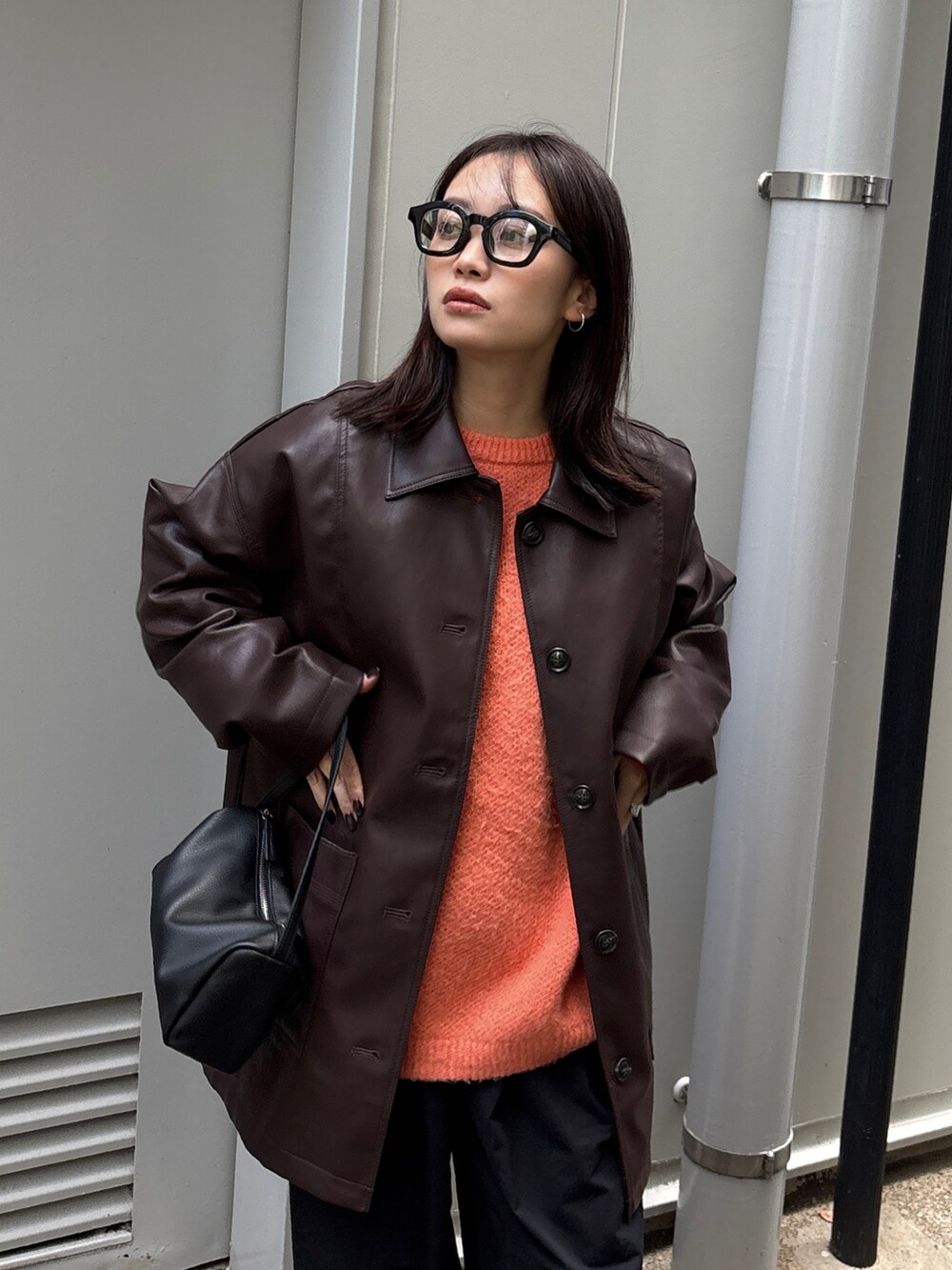 ブラウン系のカバーオール、オレンジ系のニット/セーター、ブラック系のショルダーバッグを着用したレディースの冬コーディネートの6枚目の写真