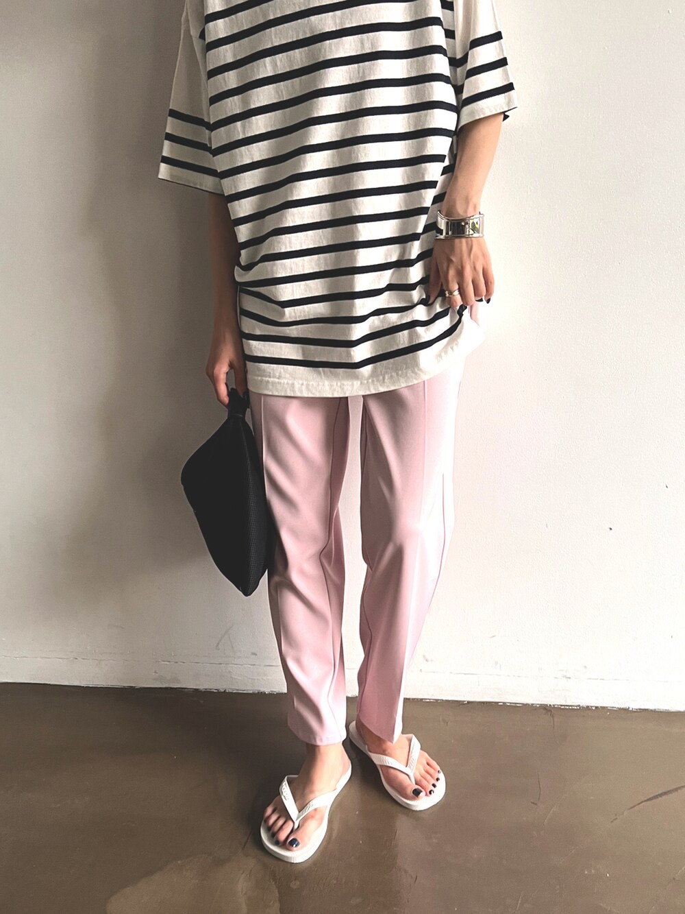 ピンク系のスラックス、ブラック系のハンドバッグ、ホワイト系のTシャツ/カットソーを着用したレディースの夏コーディネートの2枚目の写真