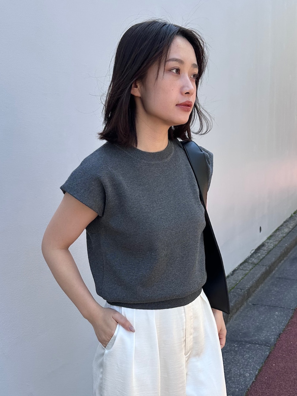 グレー系のニット/セーター、ブラック系のショルダーバッグ、ホワイト系のその他パンツを着用したレディースの春コーディネートの5枚目の写真