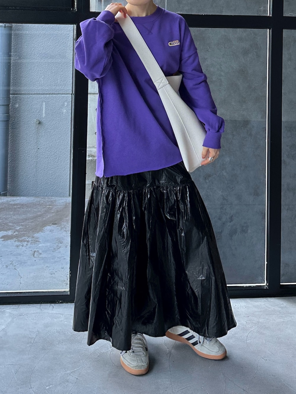 パープル系のスウェット、ブラック系のショルダーバッグ、ブラック系のスカートを着用したレディースの冬コーディネートの2枚目の写真