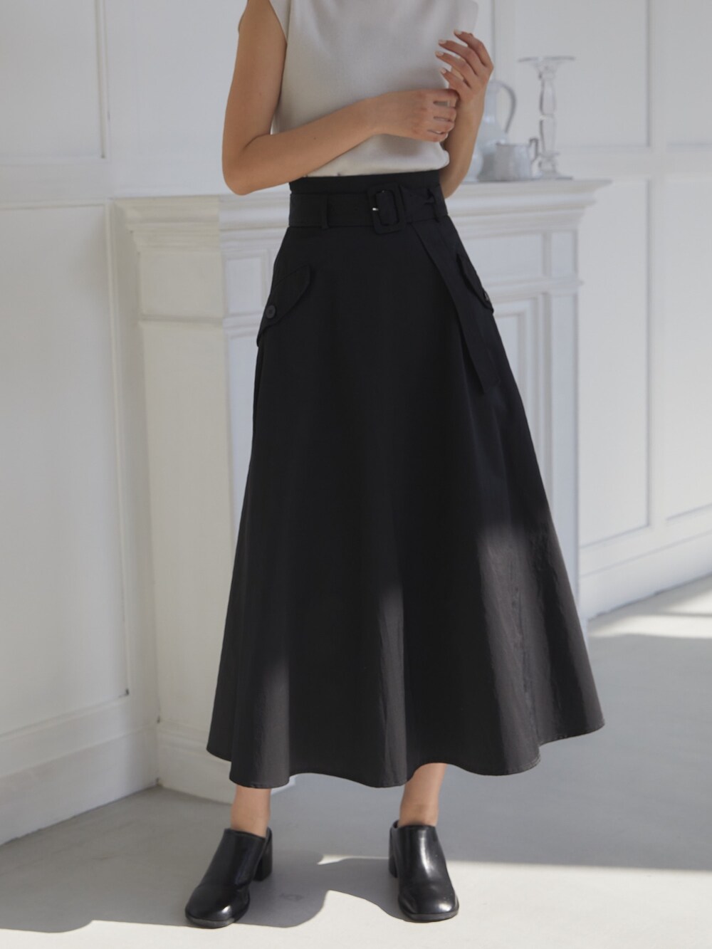 ブラック系のスカート、ホワイト系のニット/セーター、ブラック系のスリッポンを着用したレディースの夏コーディネートの5枚目の写真