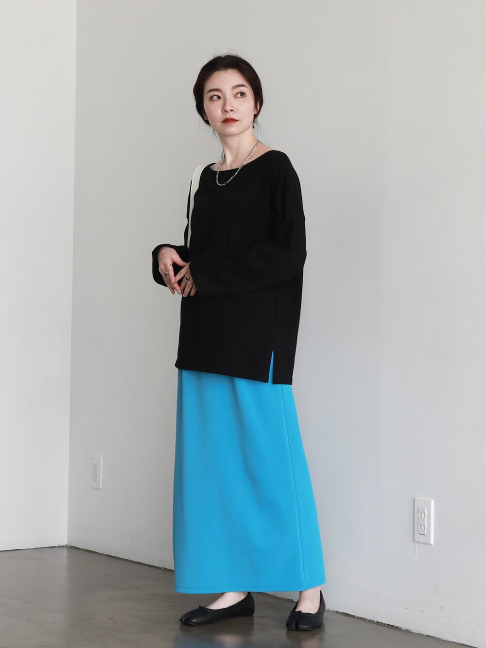 ブラック系のパンプス、ブルー系のスカート、ホワイト系のハンドバッグを着用したレディースの夏コーディネートの3枚目の写真