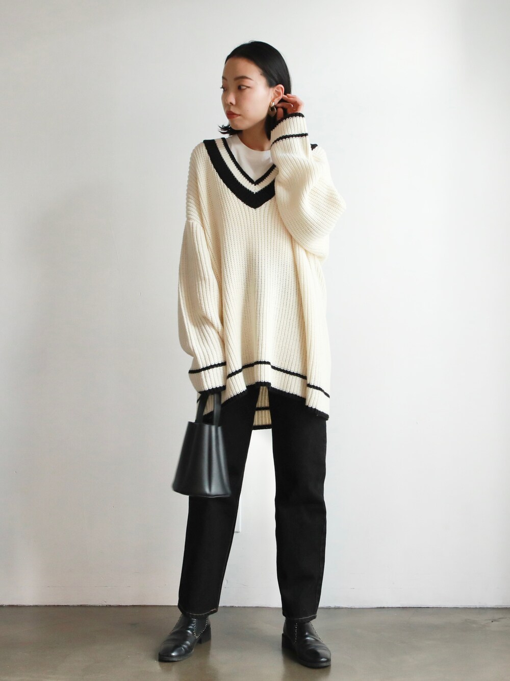 ブラック系のニット/セーター、ホワイト系のシャツ/ブラウス、ブラウン系のハンドバッグを着用したレディースの冬コーディネートの2枚目の写真