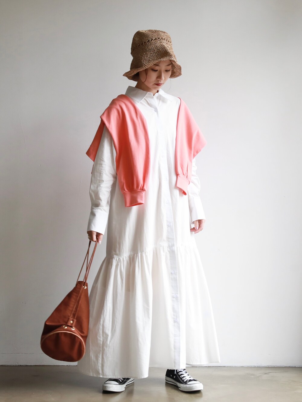 ホワイト系のシャツワンピース、ピンク系のカーディガン/ボレロ、ブラック系のスニーカーを着用したレディースの春コーディネートの3枚目の写真