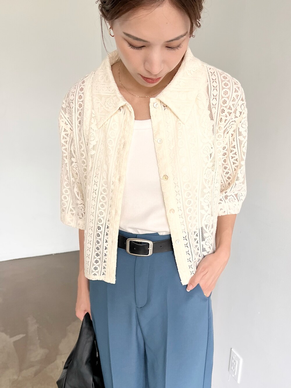 ブラック系のハンドバッグ、ブラック系のサンダル、ホワイト系のシャツ/ブラウスを着用したレディースの夏コーディネートの2枚目の写真