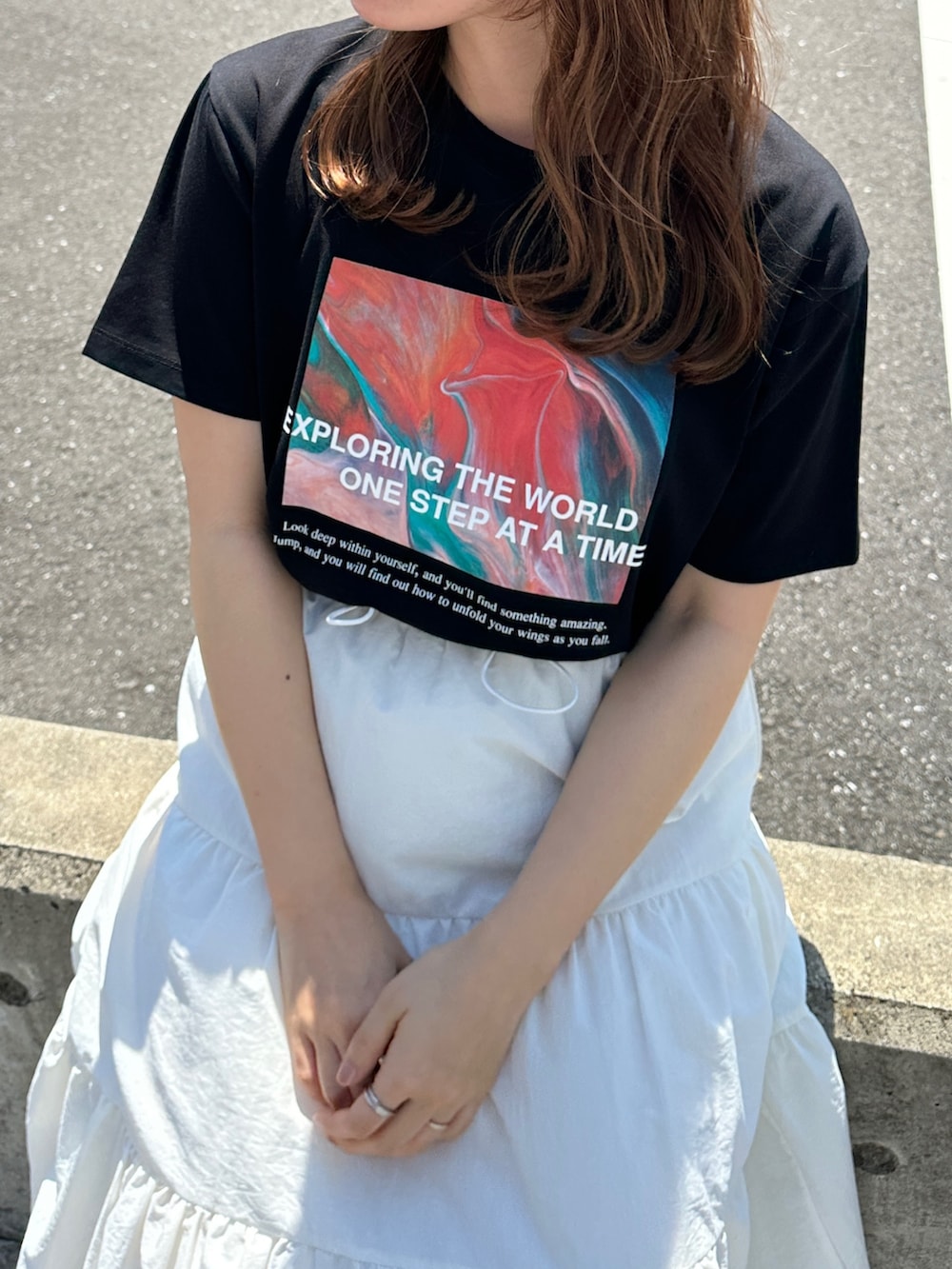 ブラック系のTシャツ/カットソー、ホワイト系のスカート、ブラック系のスニーカーを着用したレディースの夏コーディネートの3枚目の写真