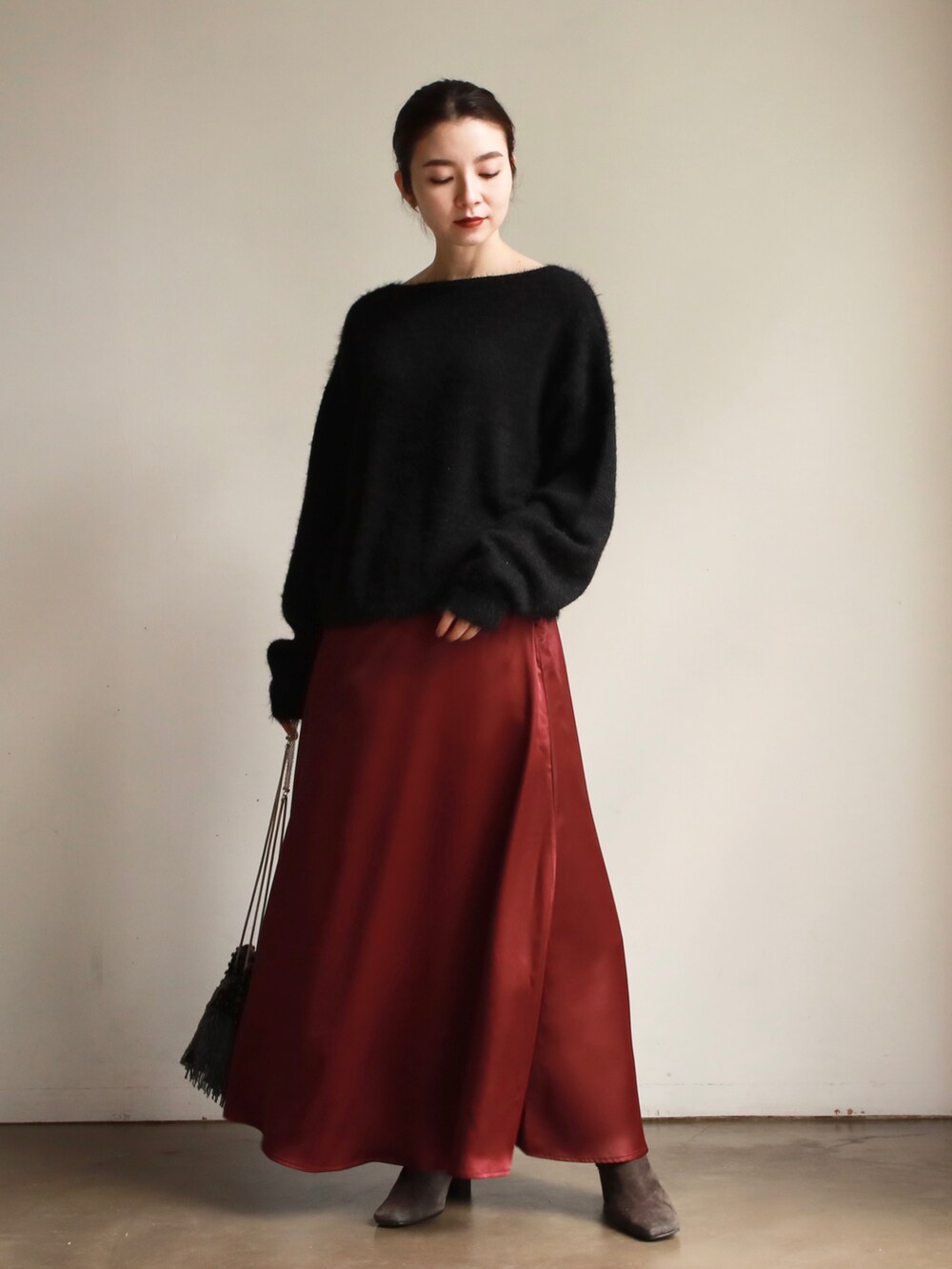 レッド系のスカート、ブラック系のニット/セーター、グレー系のブーツを着用したレディースの秋コーディネートの2枚目の写真