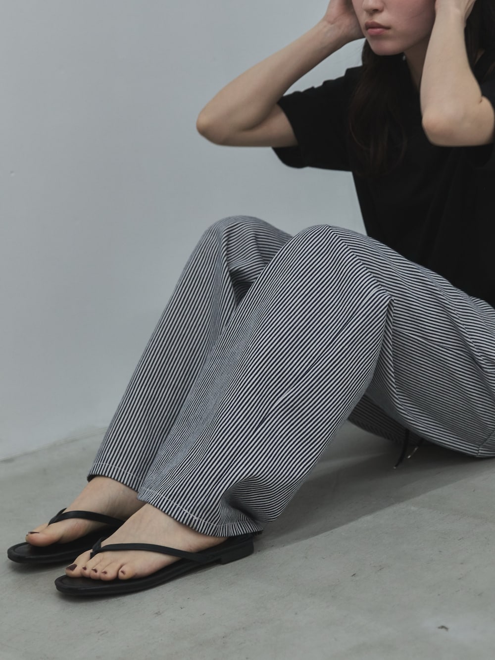 ブラック系のTシャツ/カットソー、ブラック系のデニムパンツ、ブラック系のサンダルを着用したレディースの春コーディネートの4枚目の写真