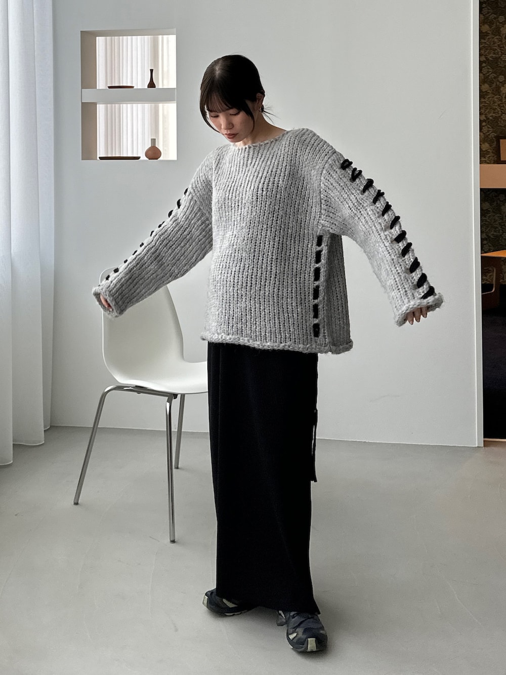 グレー系のニット/セーター、ブラック系のスカート、グリーン系のスニーカーを着用したレディースの秋コーディネートの2枚目の写真