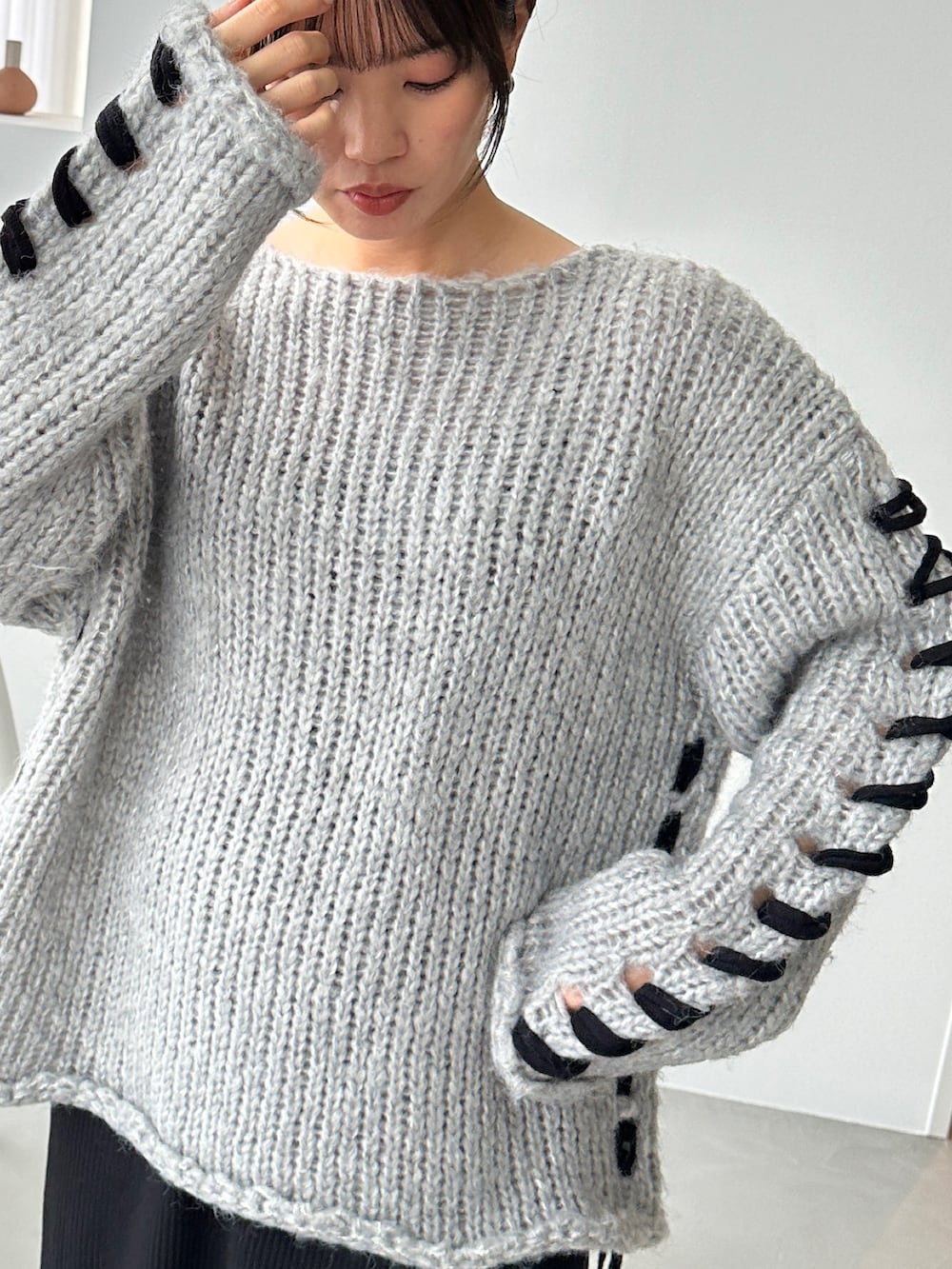 グレー系のニット/セーター、ブラック系のスカート、グリーン系のスニーカーを着用したレディースの秋コーディネートの4枚目の写真