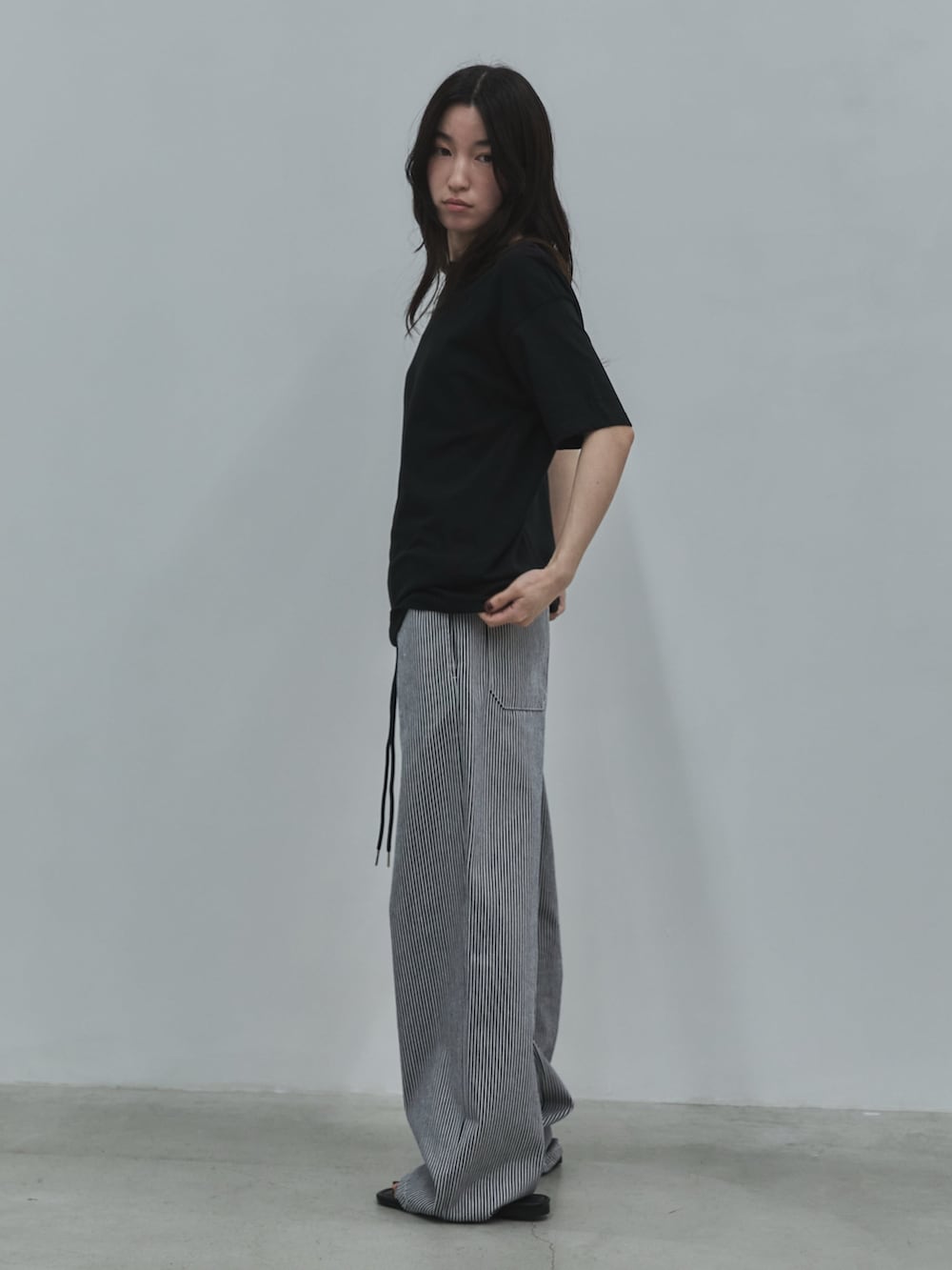ブラック系のTシャツ/カットソー、ブラック系のデニムパンツ、ブラック系のサンダルを着用したレディースの春コーディネートの2枚目の写真