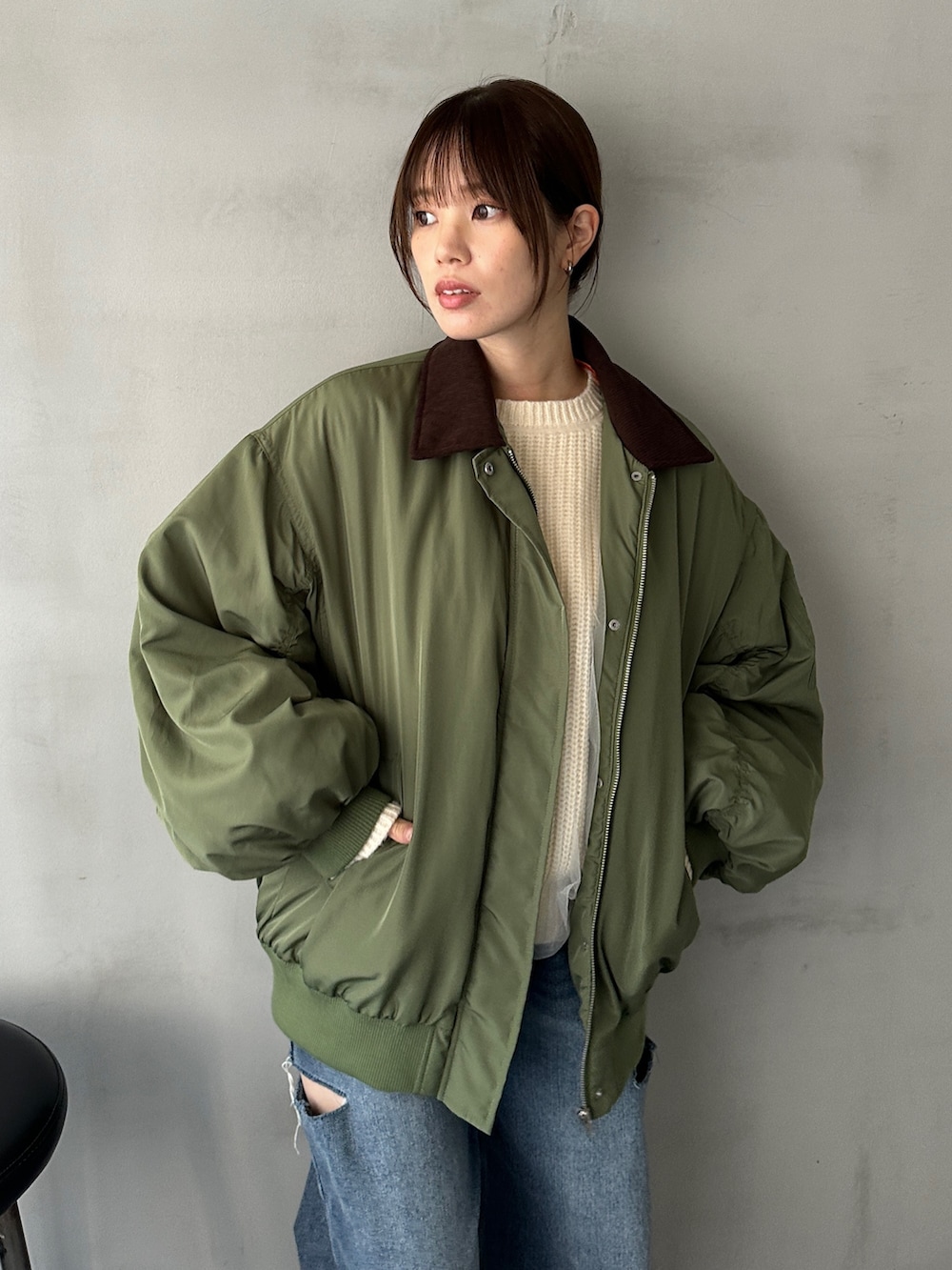 ブルー系のデニムパンツ、グリーン系のMA-1、ホワイト系のニット/セーターを着用したレディースの冬コーディネートの5枚目の写真