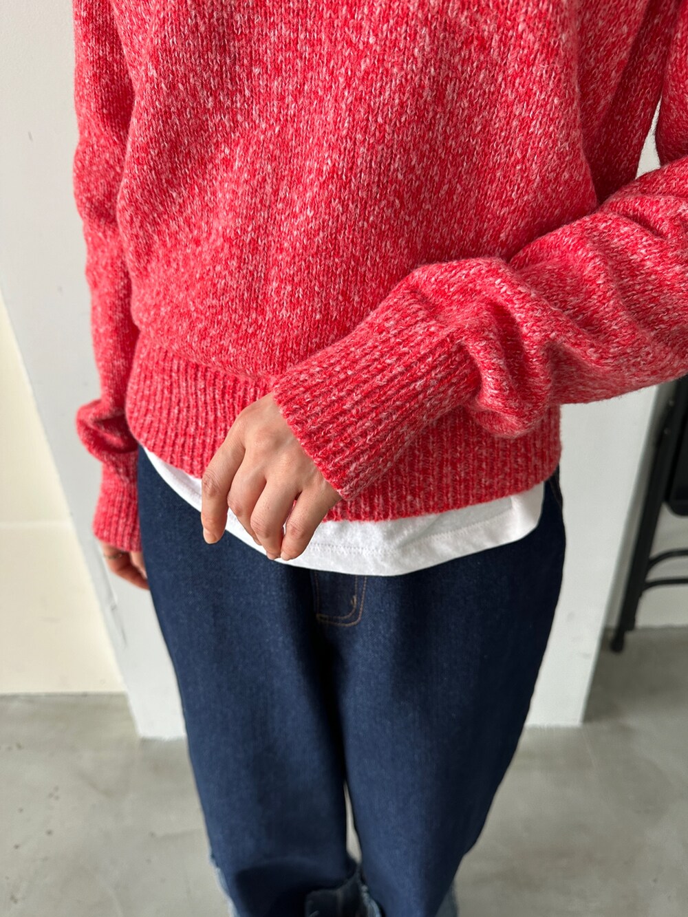 レッド系のニット/セーター、ブルー系のデニムパンツを着用したレディースの秋コーディネートの5枚目の写真