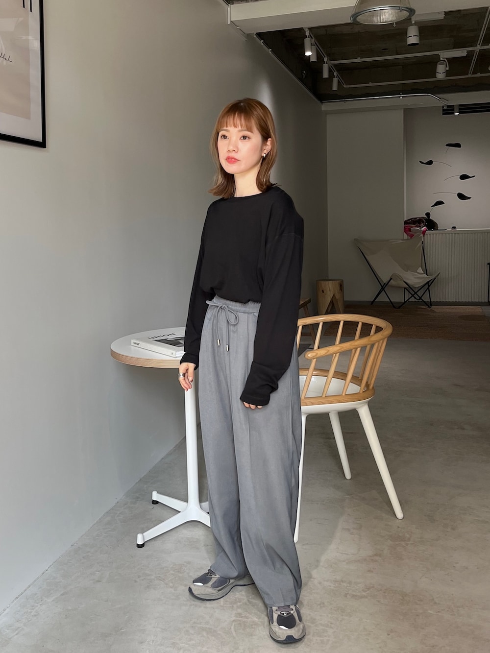 ブラック系のスラックス、ブラック系のサンダル、グレー系のニット/セーターを着用したレディースの春コーディネートの2枚目の写真