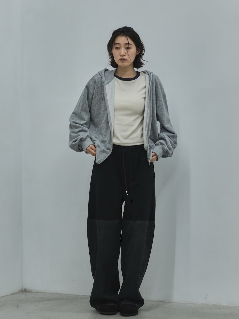 グレー系のパーカー、ホワイト系のTシャツ/カットソー、ブラック系のデニムパンツを着用したレディースの秋コーディネートの4枚目の写真