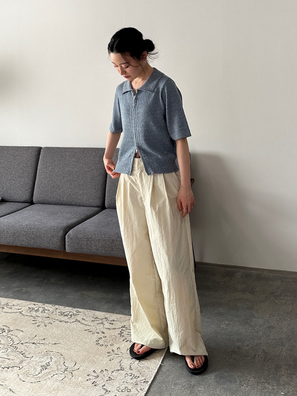 ブルー系のニット/セーター、ホワイト系のその他パンツ、ブラック系のサンダルを着用したレディースの夏コーディネートの2枚目の写真