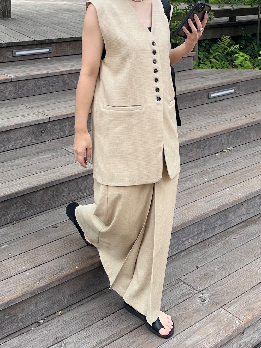 ホワイト系のベスト、ホワイト系のスカート、ブラック系のサンダルを着用したレディースの夏コーディネートの5枚目の写真