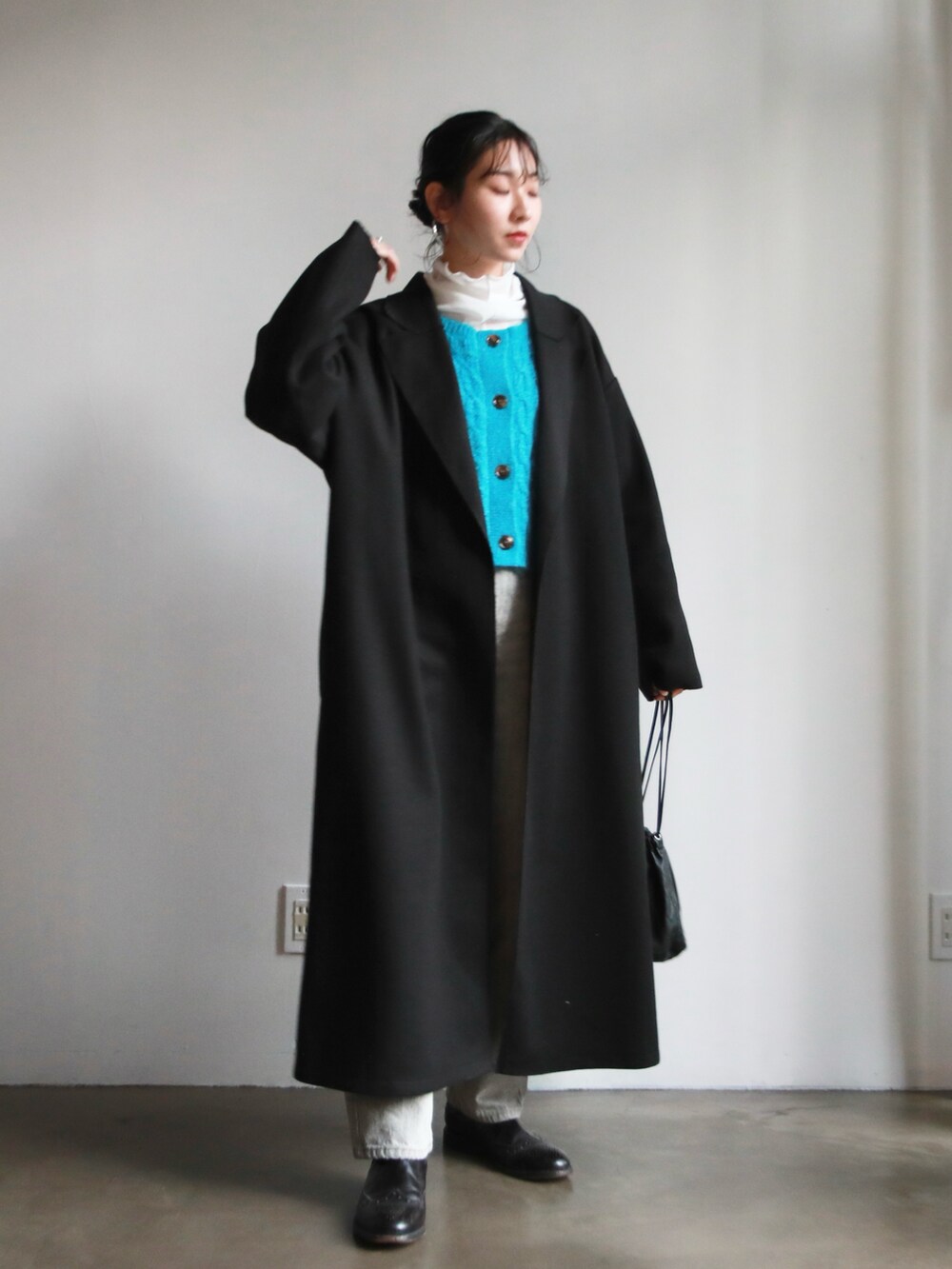 グレー系のデニムパンツ、ブルー系のカーディガン/ボレロ、ブラック系のハンドバッグを着用したレディースの冬コーディネートの2枚目の写真