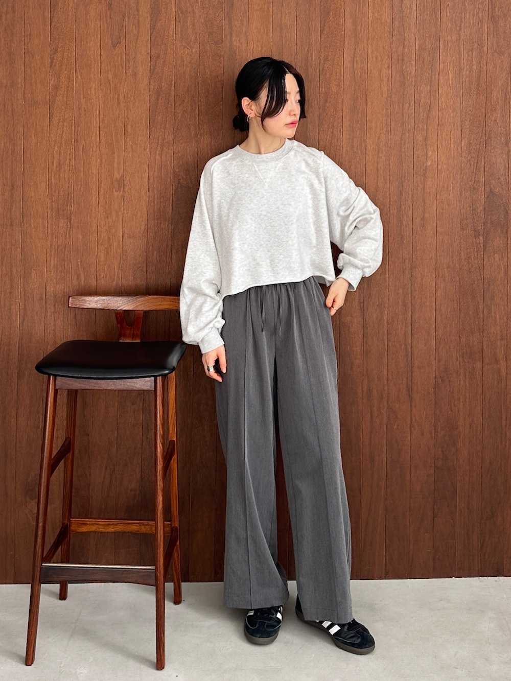 グレー系のスウェット、グレー系のスラックス、ブラック系のスニーカーを着用したレディースの秋コーディネートの2枚目の写真