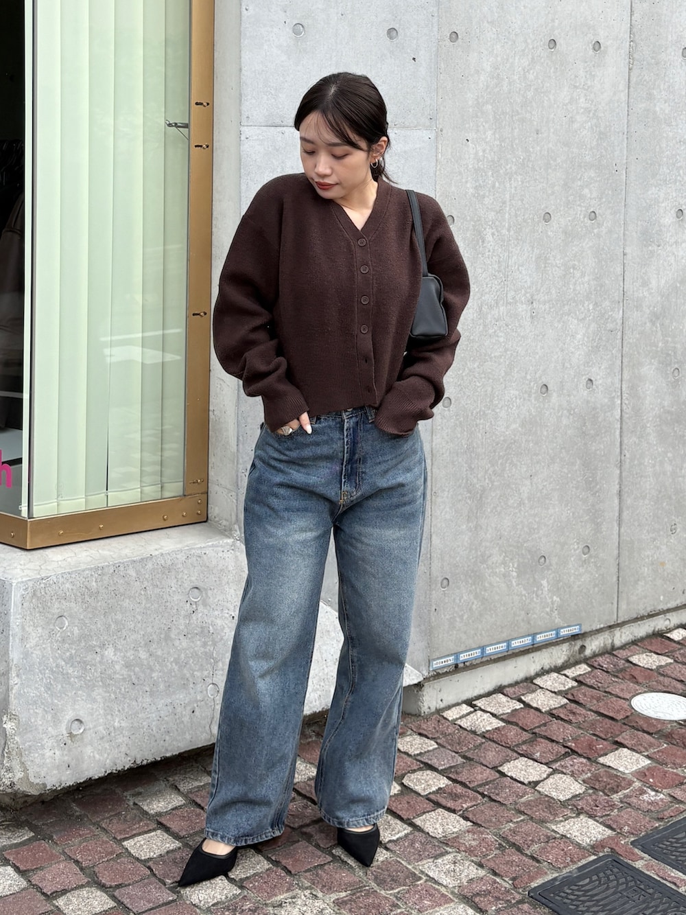 ブラウン系のカーディガン/ボレロ、ブルー系のデニムパンツ、ブラック系のショルダーバッグを着用したレディースの冬コーディネートの2枚目の写真