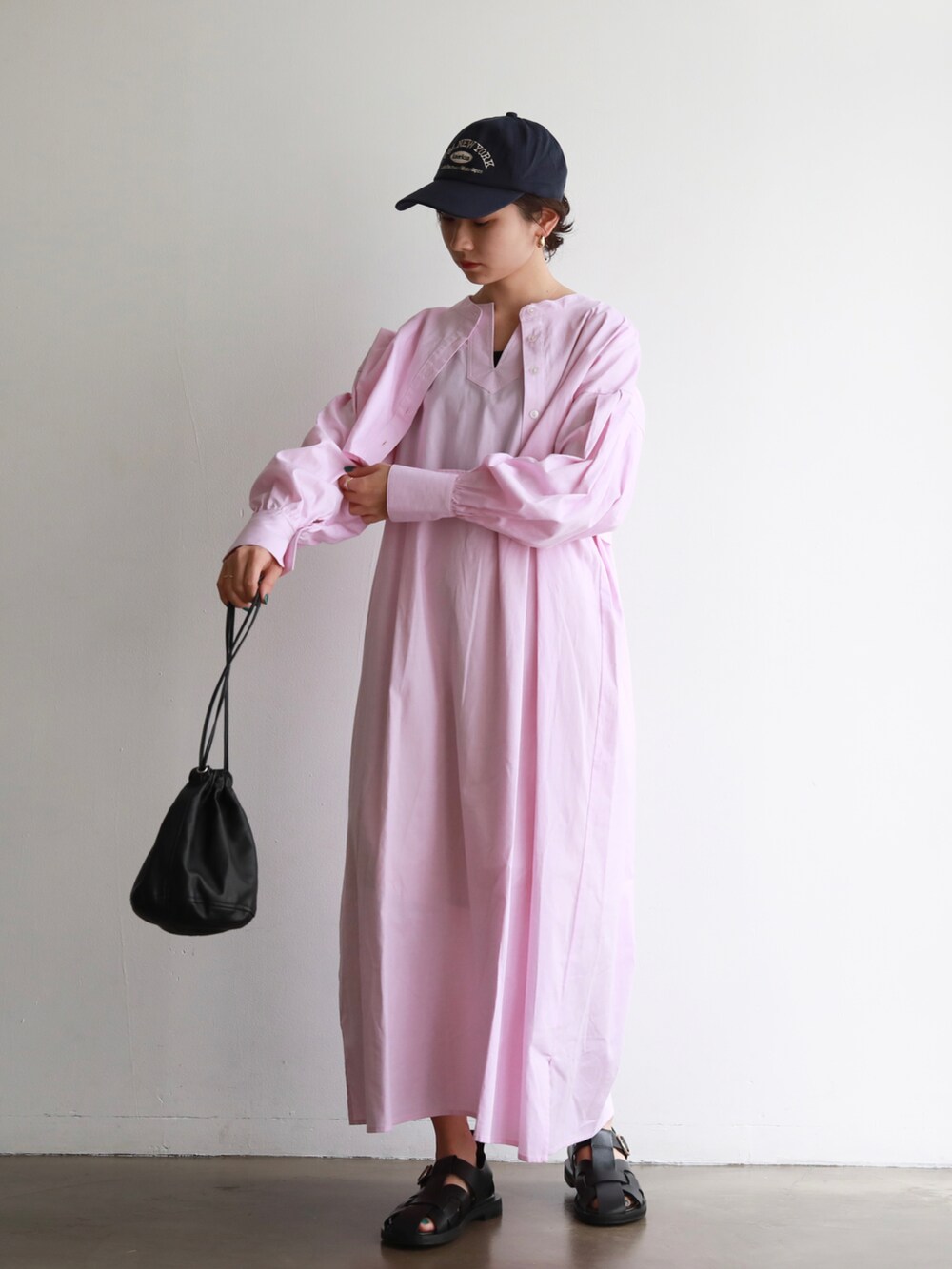 ブラック系のハンドバッグ、ピンク系のシャツワンピース、ブルー系のキャップを着用したレディースの夏コーディネートの2枚目の写真