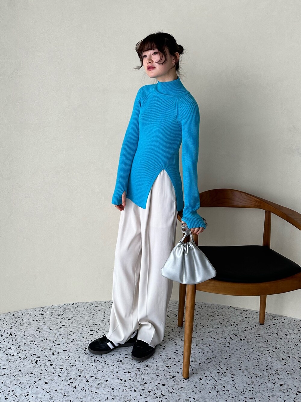 ブラック系のチェスターコート、ブルー系のニット/セーター、シルバー系のショルダーバッグを着用したレディースの冬コーディネートの4枚目の写真