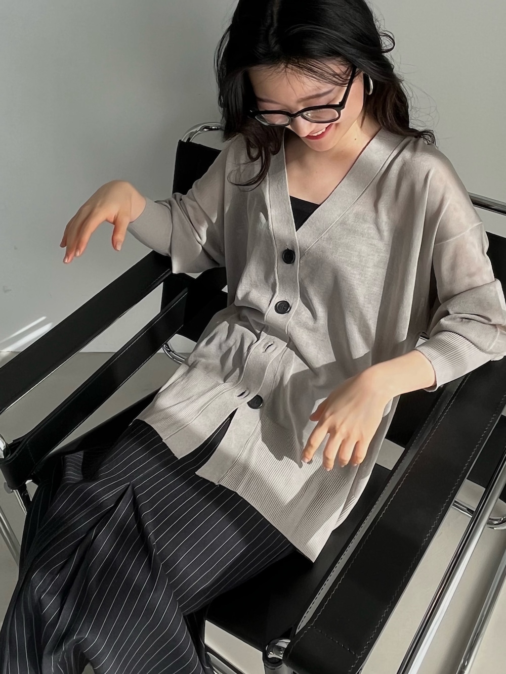 グレー系のカーディガン/ボレロ、ブルー系のスカート、ブラック系のメガネを着用したレディースの冬コーディネートの2枚目の写真