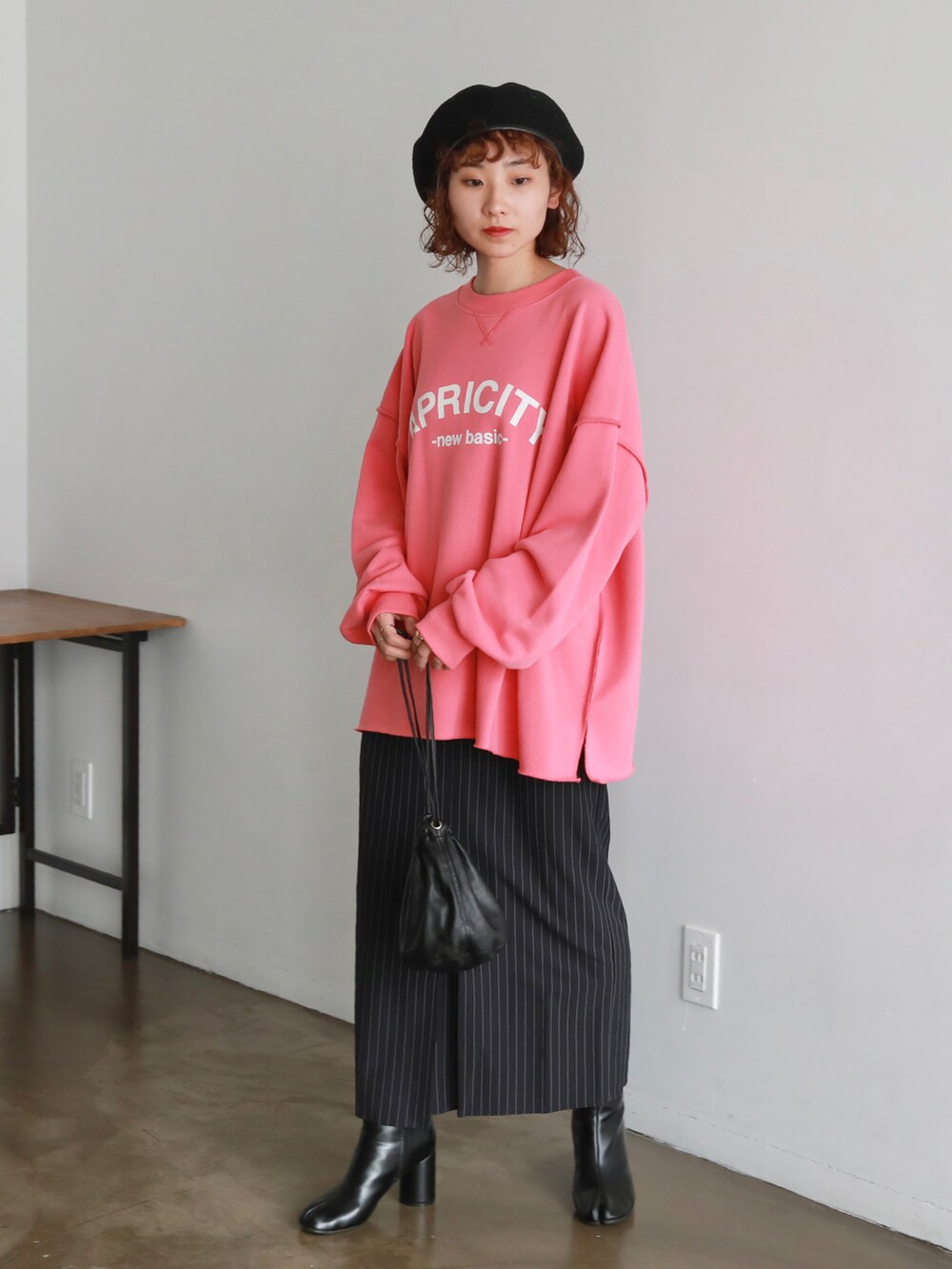 ピンク系のスウェット、ブラック系のハンドバッグ、ブルー系のスカートを着用したレディースの秋コーディネートの2枚目の写真