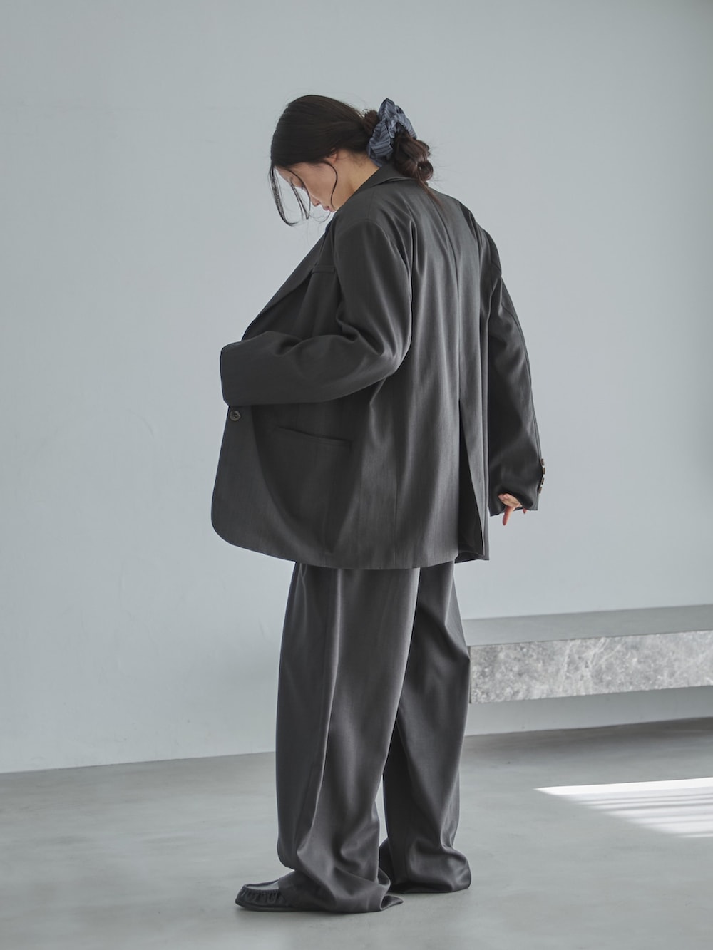 グレー系のテーラードジャケット、ホワイト系のカーディガン/ボレロ、グレー系のスラックスを着用したレディースの冬コーディネートの3枚目の写真