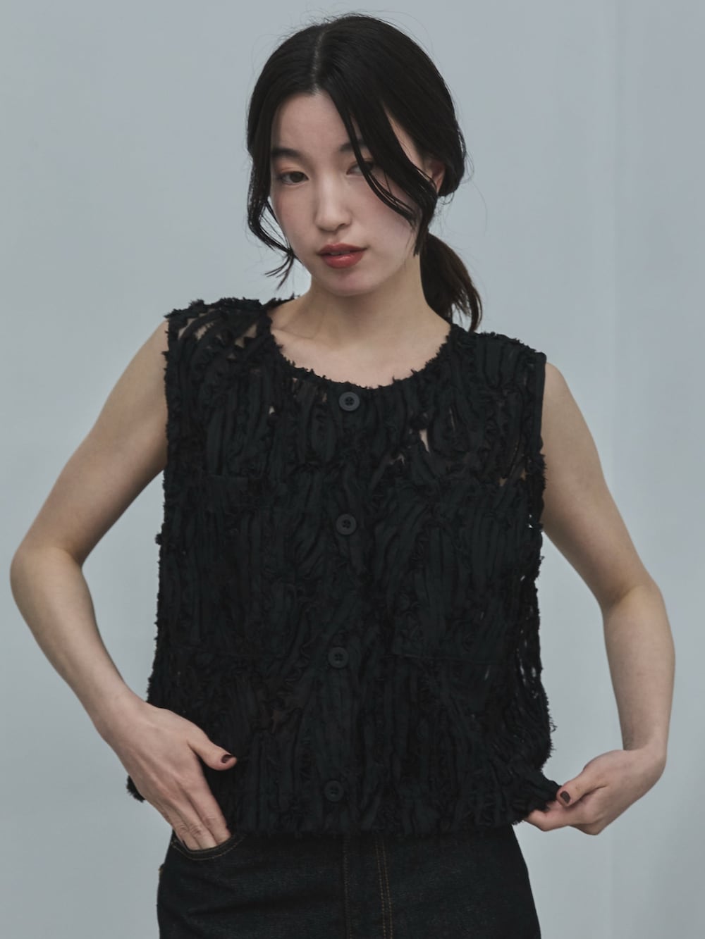 ブラック系のベスト、ブラック系のデニムパンツ、ブラック系のサンダルを着用したレディースの夏コーディネートの4枚目の写真