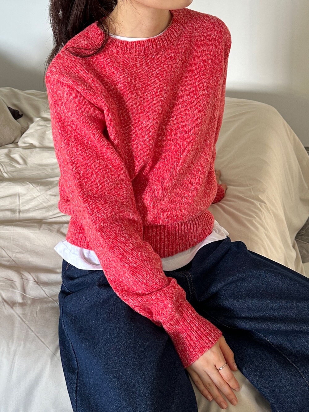 レッド系のニット/セーター、ブルー系のデニムパンツを着用したレディースの秋コーディネートの2枚目の写真