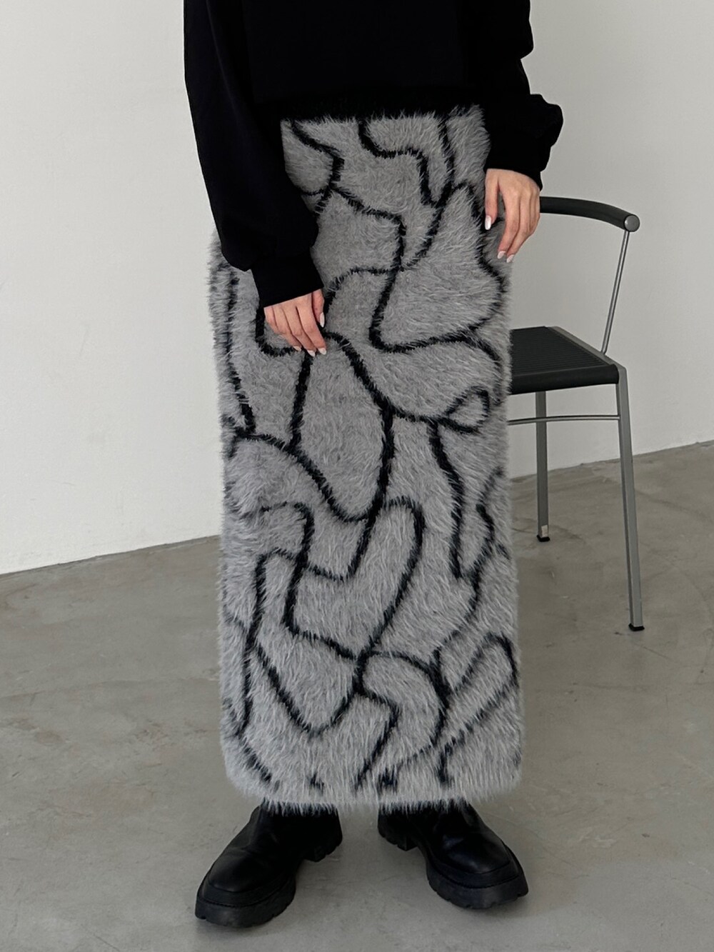 グレー系のスカート、ブラック系のブーツ、ブラック系のスウェットを着用したレディースの冬コーディネートの5枚目の写真