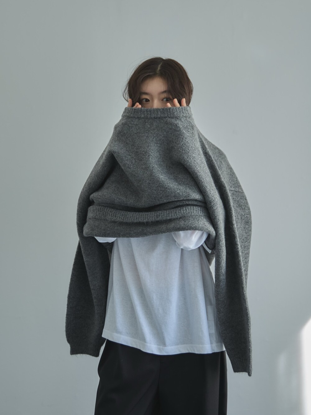 グレー系のニット/セーター、ホワイト系のTシャツ/カットソー、ブラック系のスラックスを着用したレディースの秋コーディネートの5枚目の写真