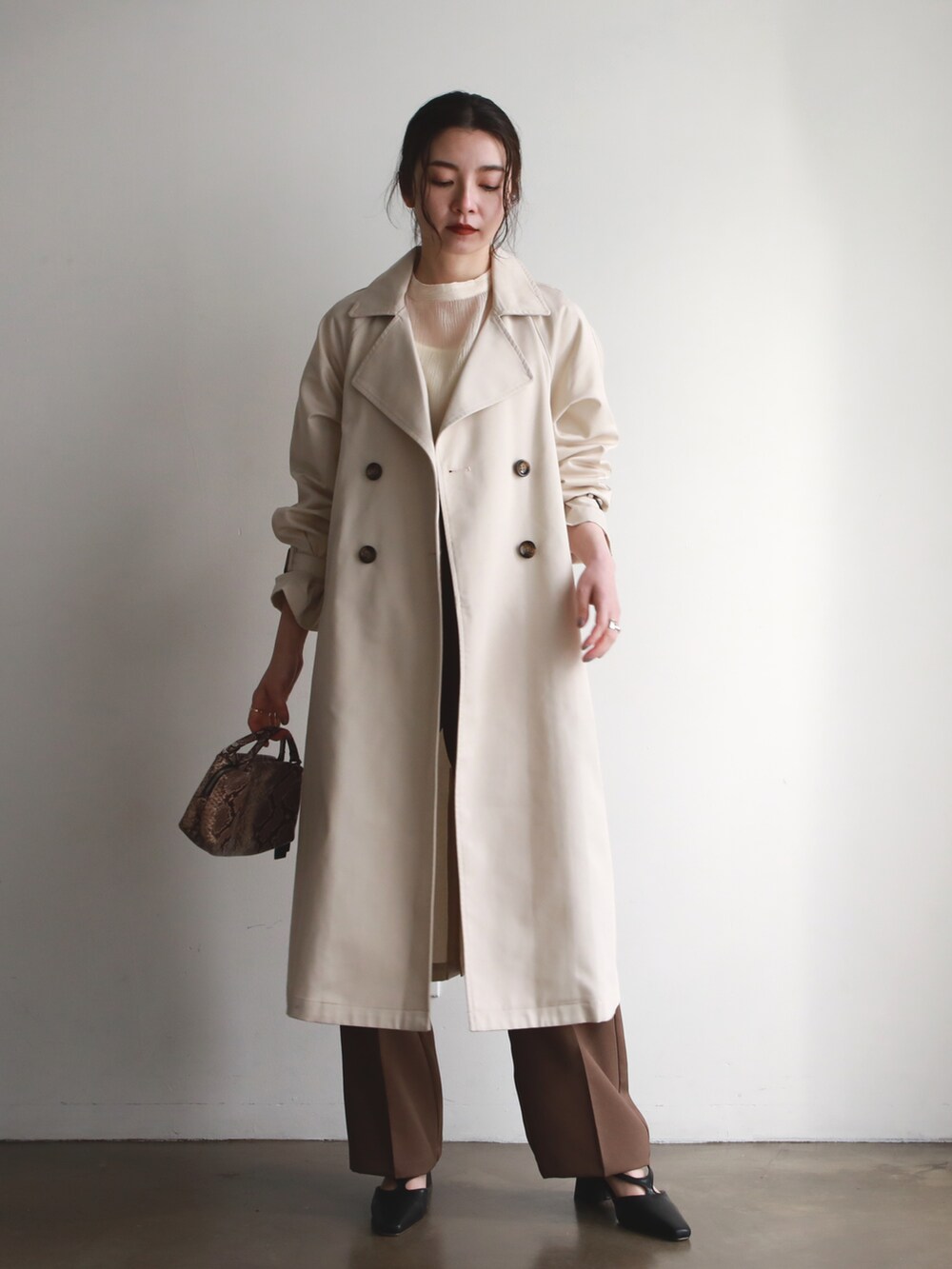 ブラック系のローファー、ホワイト系のトレンチコート、グリーン系のカーディガン/ボレロを着用したレディースの春コーディネートの4枚目の写真