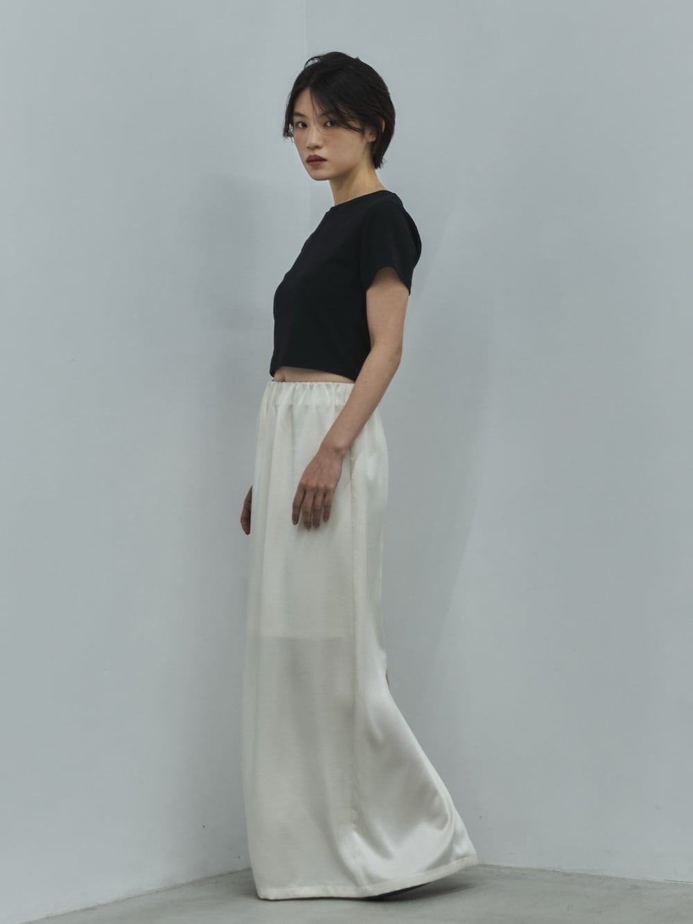 ブラック系のTシャツ/カットソー、ホワイト系のスカート、ブラック系のサンダルを着用したレディースの夏コーディネートの2枚目の写真