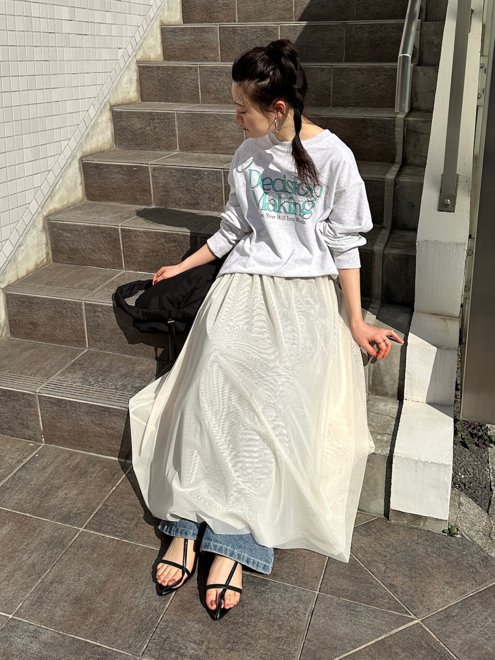 ベージュ系のスウェット、ホワイト系のスカート、ブルー系のデニムパンツを着用したレディースの春コーディネートの3枚目の写真