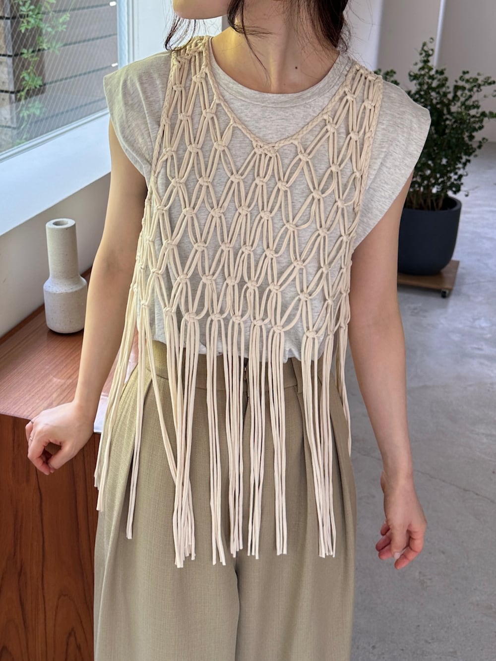 ホワイト系のベスト、ベージュ系のタンクトップ、ベージュ系のスラックスを着用したレディースの夏コーディネートの3枚目の写真