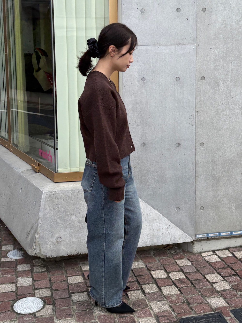 ブラウン系のカーディガン/ボレロ、ブルー系のデニムパンツ、ブラック系のショルダーバッグを着用したレディースの冬コーディネートの3枚目の写真