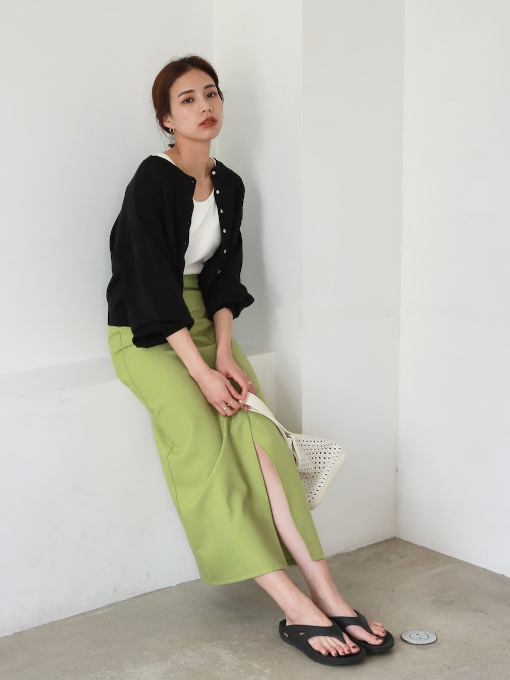 ブラック系のサンダル、ホワイト系のトートバッグ、グリーン系のスカートを着用したレディースの夏コーディネートの2枚目の写真