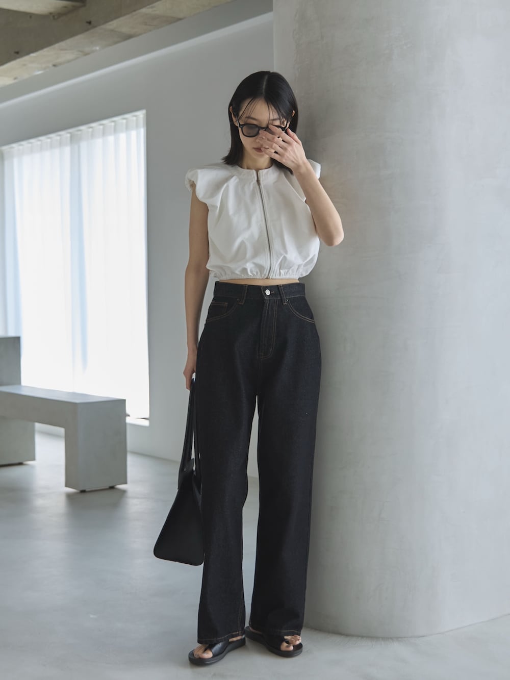 ブラック系のデニムパンツ、ホワイト系のシャツ/ブラウス、ブラック系のボストンバッグを着用したレディースの夏コーディネートの2枚目の写真