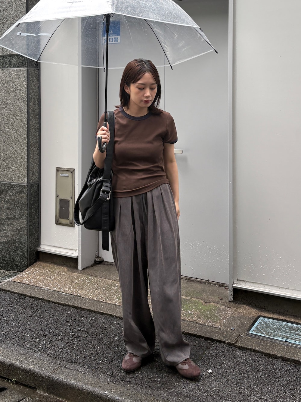 ブラウン系のTシャツ/カットソー、グレー系のスラックス、ブラック系のショルダーバッグを着用したレディースの夏コーディネートの3枚目の写真